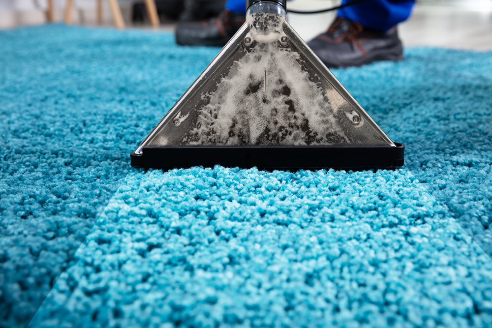 A Person Cleaning Carpet With Vacuum Cleaner