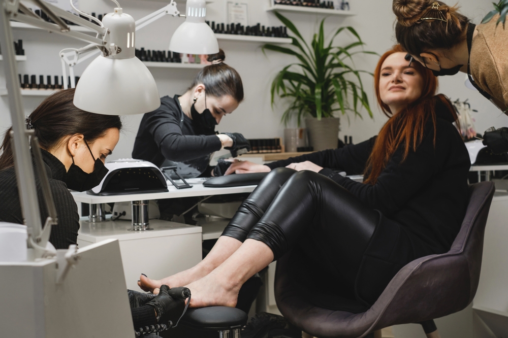 Beautiful ginger girl enjoying beauty routines simultaneously, having correction of eyebrows, manicure and pedicure in a beauty salon in Melbourne in an hour.