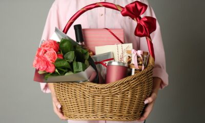 Close-up of woman holding a wicker basket filled with luxury gourmet food hamper gifts against a grey background